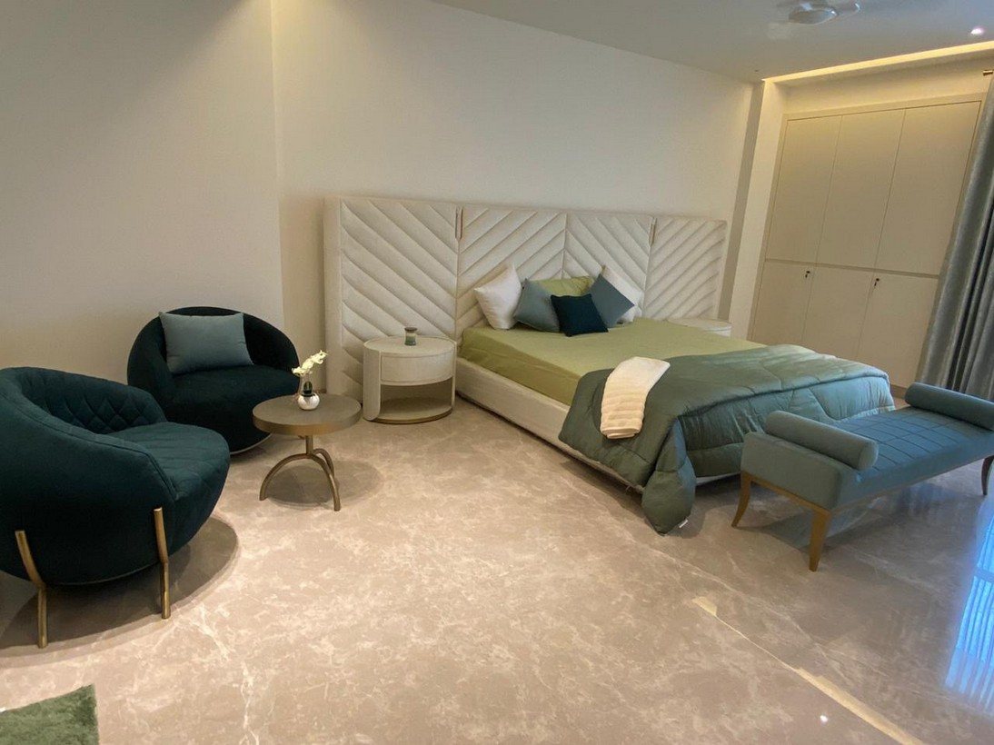 Bedroom with an upholstered headboard wall and green velvet seating