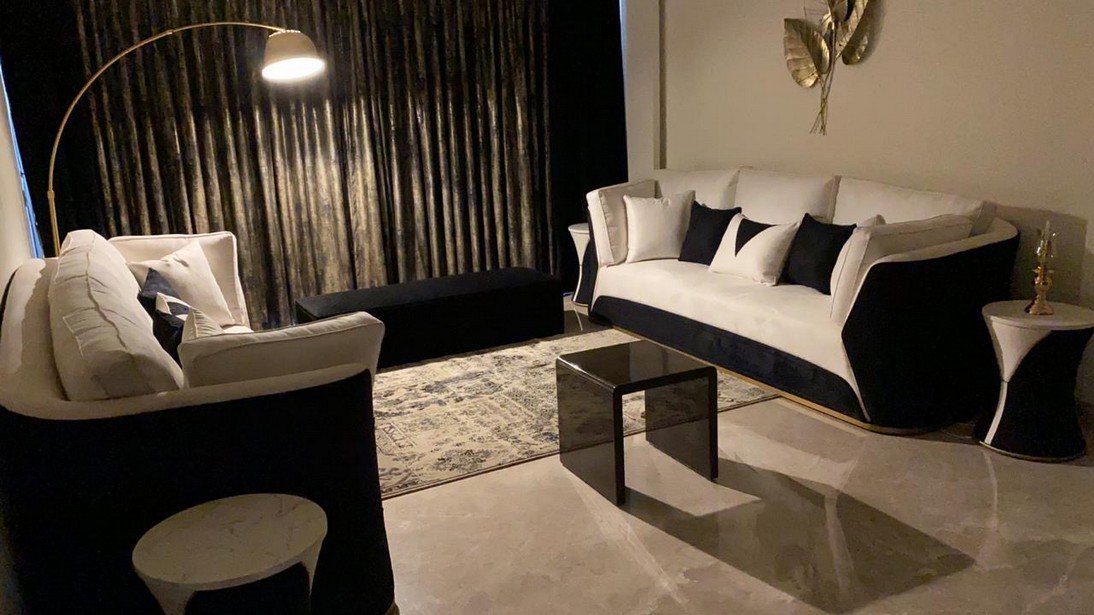 Residential lounge with cream sofas, dark drapery and a brass wall sculpture