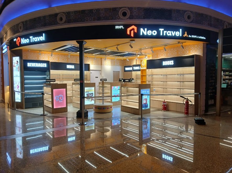 Curved travel retail storefront with illuminated signage and timber shelving